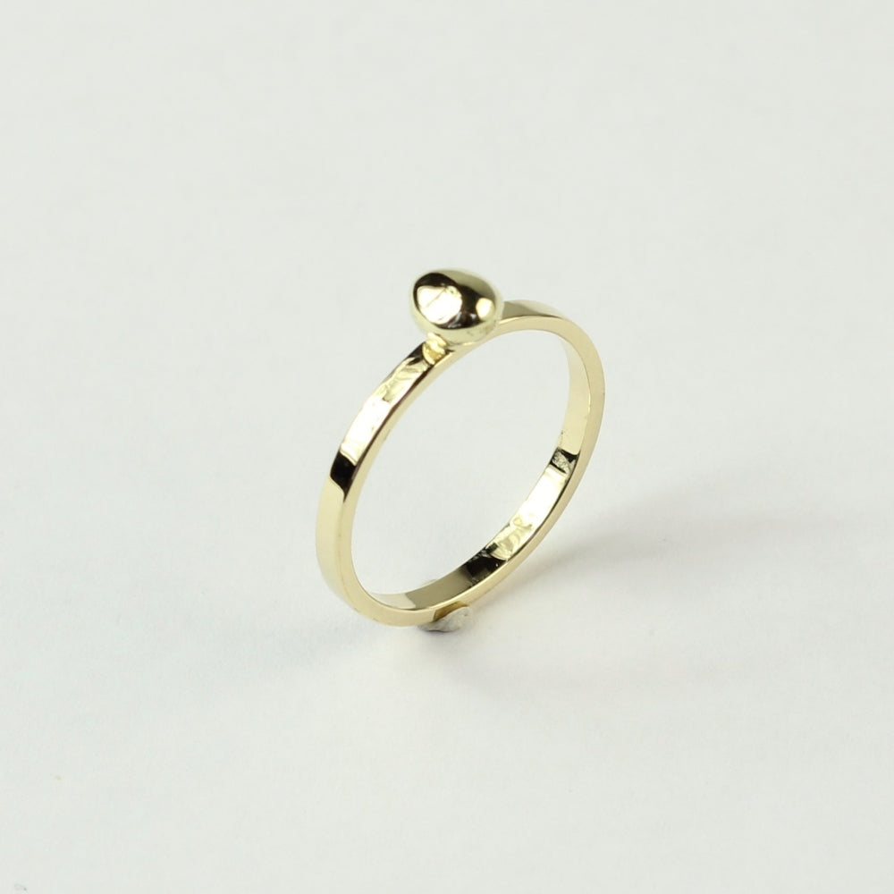 Schuin zijaanzicht minimalistische gouden ring met gouden steentje uit collectie Essentials. Op een witte ondergrond