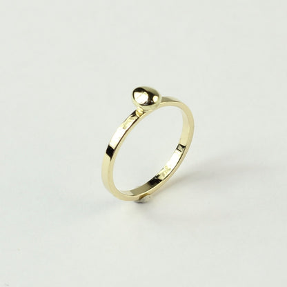 Schuin zijaanzicht minimalistische gouden ring met gouden steentje uit collectie Essentials. Op een witte ondergrond