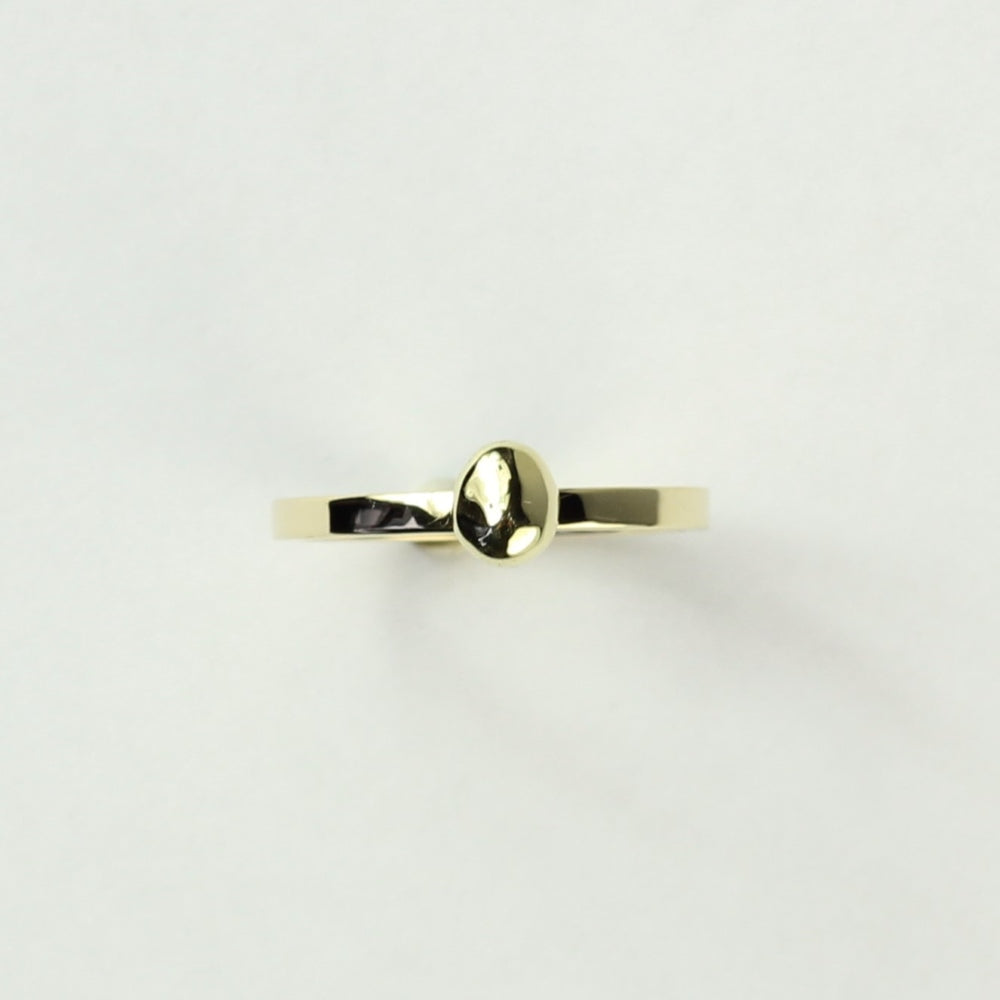 Bovenaanzicht minimalistische gouden ring met gouden steentje uit collectie Essentials. Op een witte ondergrond