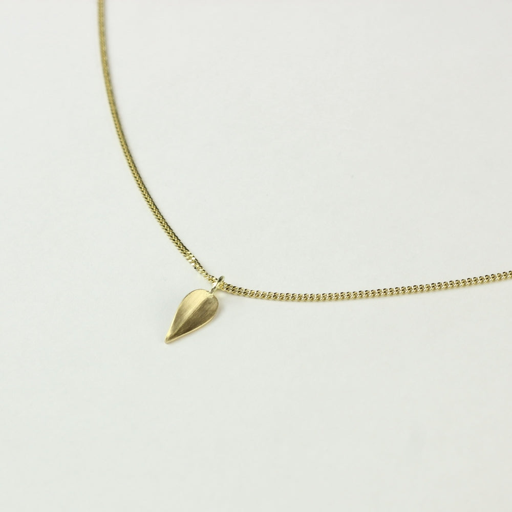 Close up van 14 k gouden hanger Leaves, een minimalistisch blaadje met lichte vouw in het midden. aan gouden ketting.