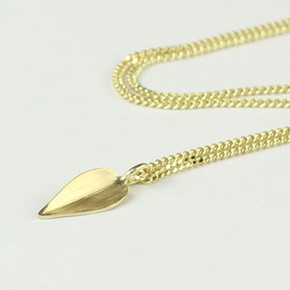 Close up van 14 k gouden hanger Leaves, een minimalistisch blaadje met lichte vouw in het midden. aan gouden ketting.