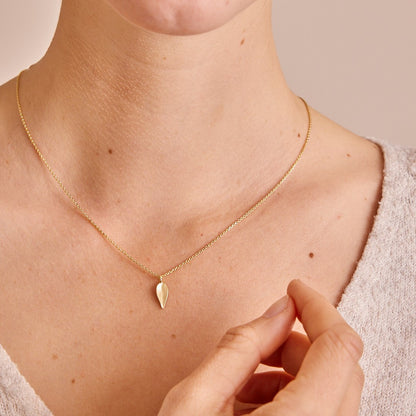 Model draagt 14 karaat geelgouden geslepen anker collier om haar hals, met daaraan een blaadjes hanger uit de collectie Leaves.