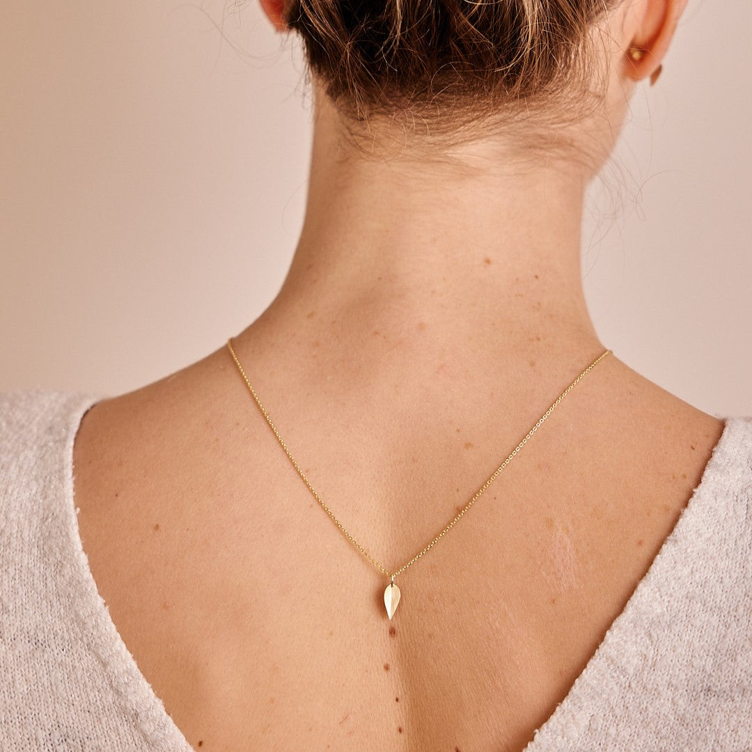 Model draagt  achterstevoren een 14 k gouden hanger Leaves, een minimalistisch blaadje.